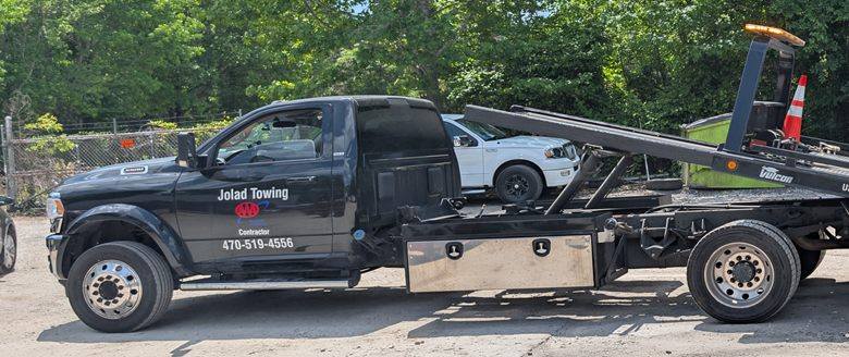 Jolad Towing flatbed truck transporting a vehicle